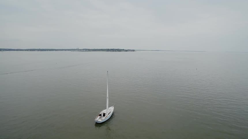 A white boat sailing on the ocean towards land