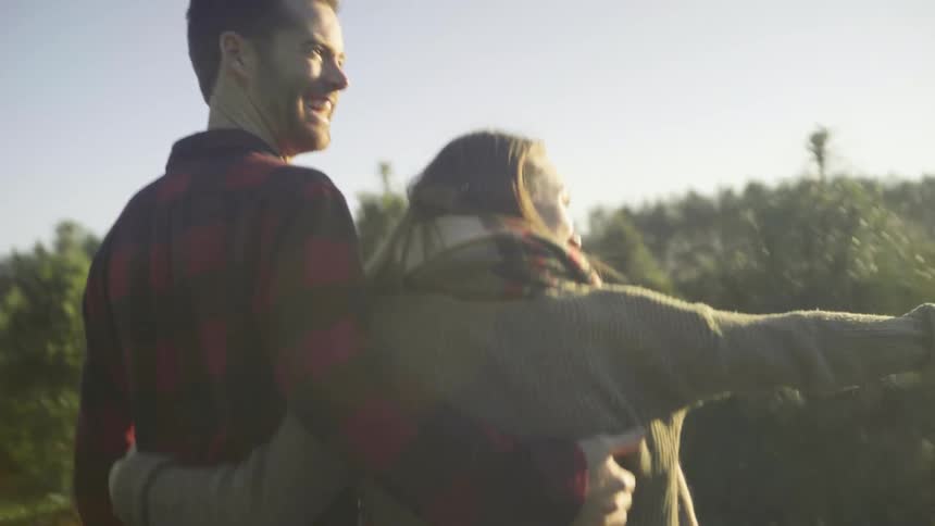 Couple happily walking and jumping through an area while looking for a christmas tree