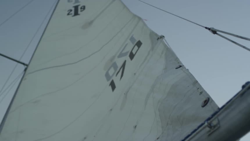 A white sail flutters in the breeze