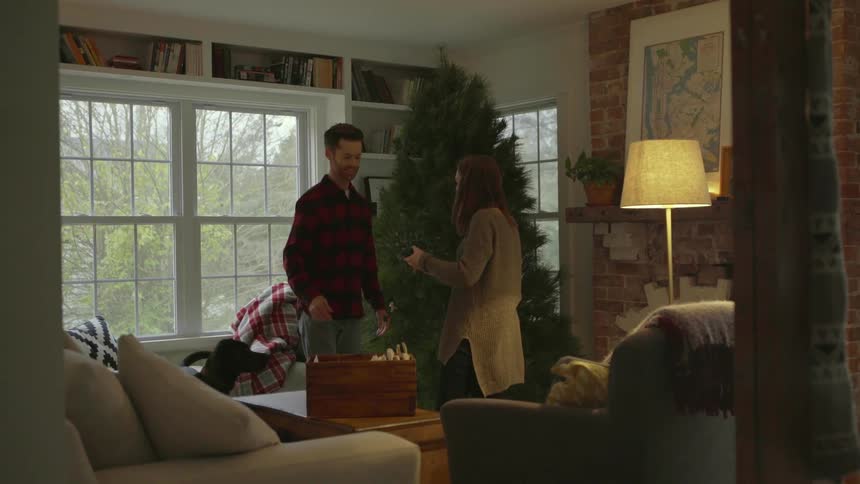 A man and woman decorate a christmas tree