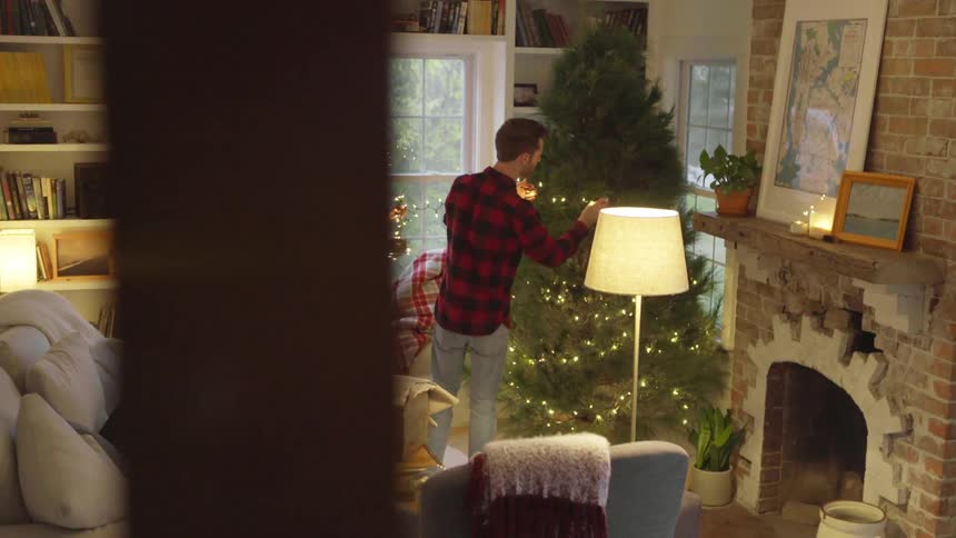 A man and woman decorate a christmas tree