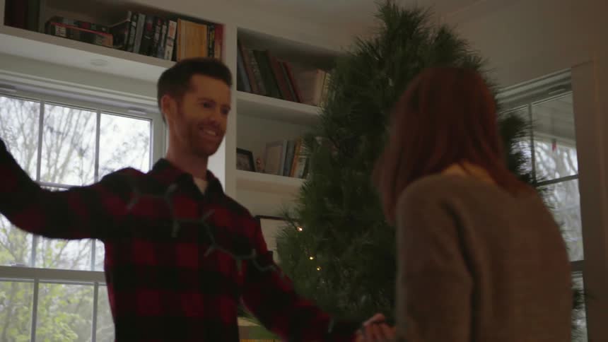 A man and woman decorate a christmas tree