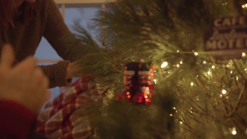 A man and woman decorate a christmas tree