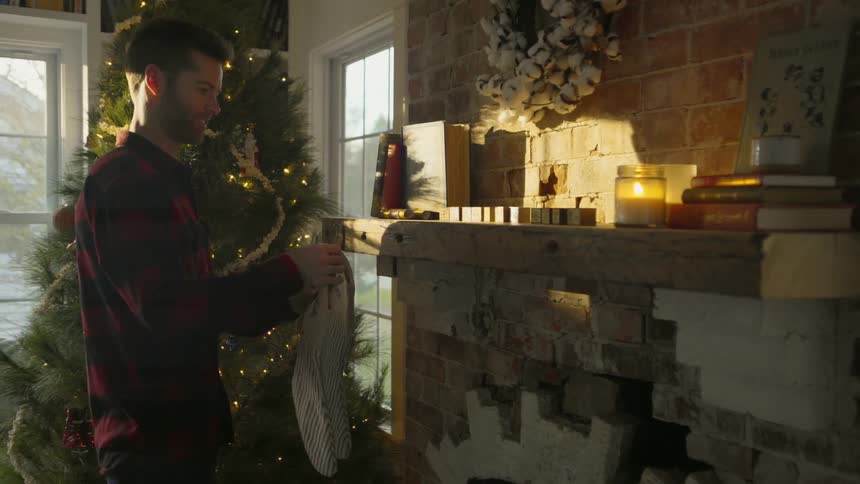 A man hangs christmas stockings on a fireplace
