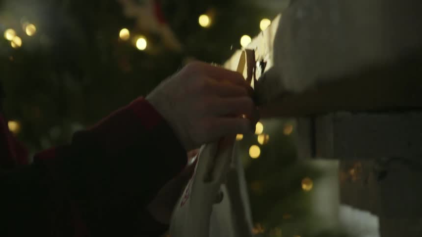 A man hangs two christmas stockings on the mantel