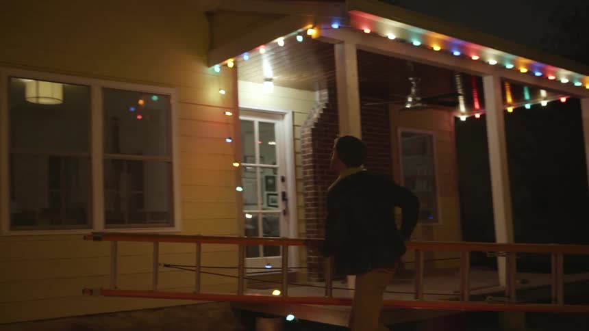 Man places a ladder on the side of a front porch