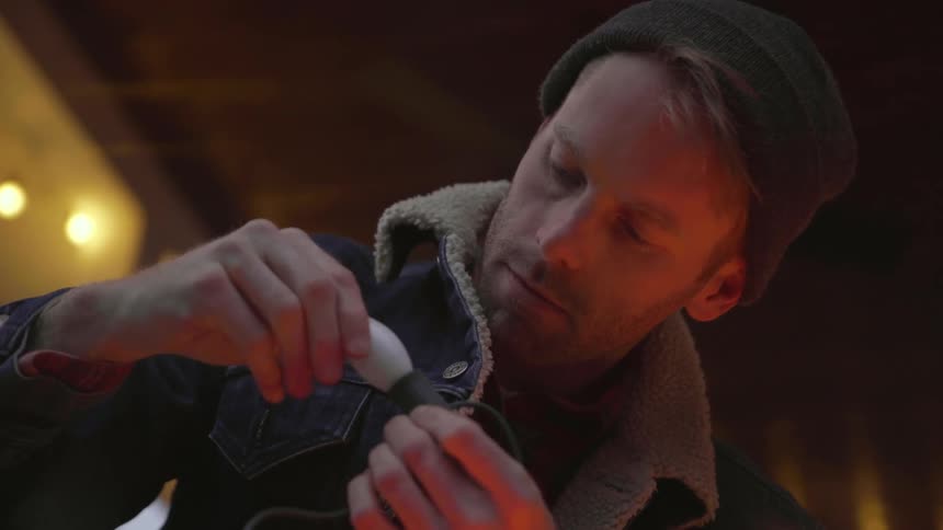 A man screws a bulb onto a strand of christmas lights