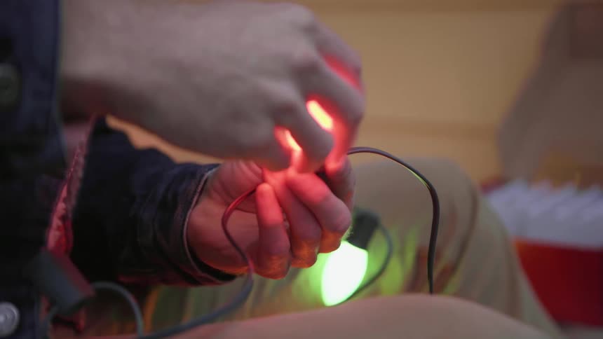 A man is getting bulbs from a box and putting them on a string of lights