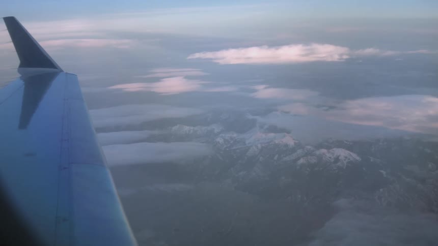 A snow covered mountain is seen from an airplane window