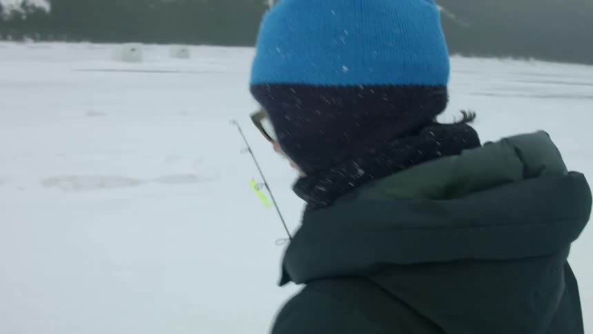 A woman goes fishing in the snow