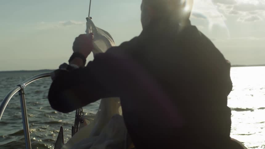 A man begins to prepare a sail to be raised on a boat