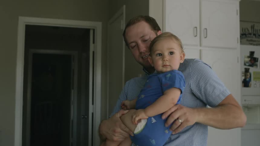 A man holds a baby in a kitchen