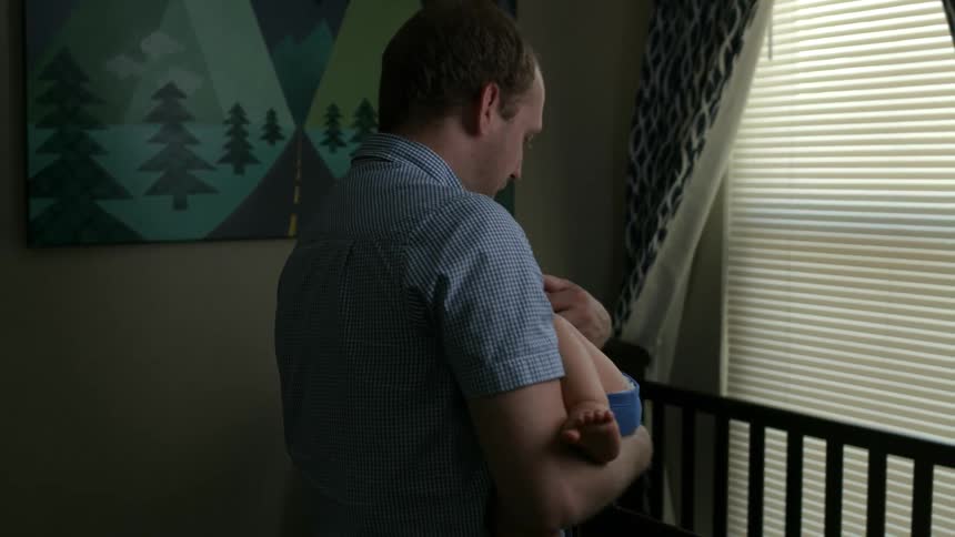 A man places a baby in a crib