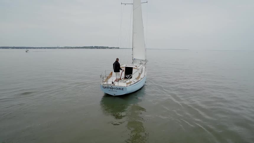 A man is steering a boat on a cloudy day