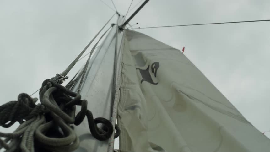 A white sail is lifted on a boat