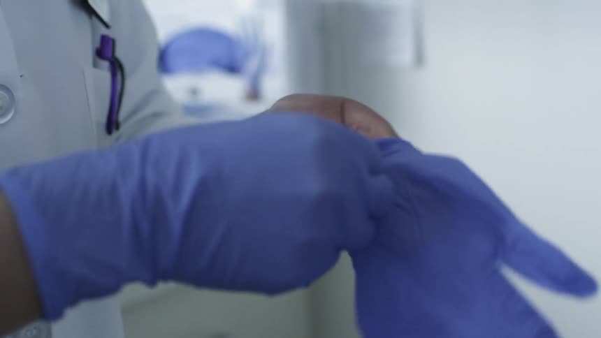 A person puts on blue rubber gloves