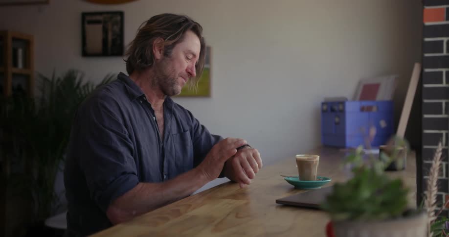 A man sips a drink while working on a laptop