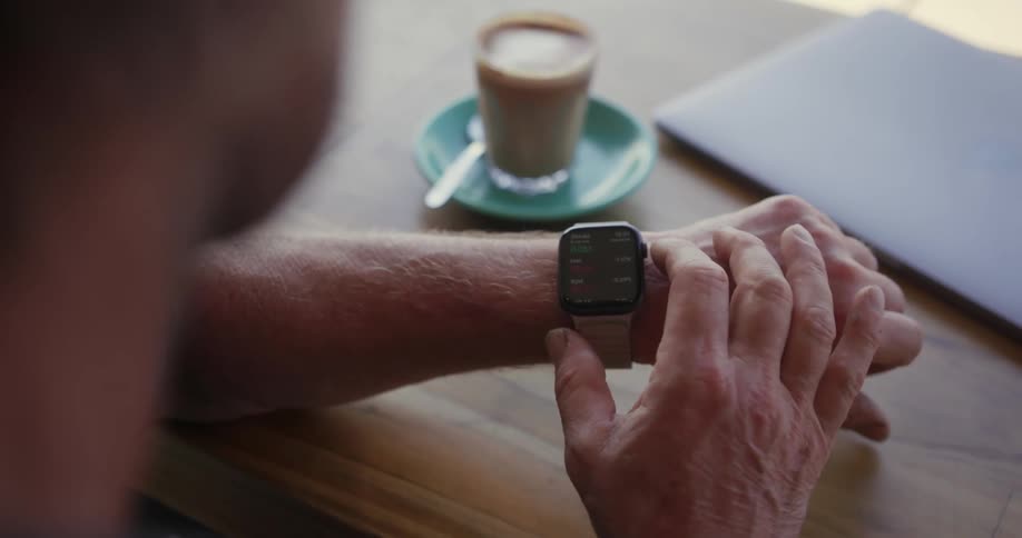 A man sits at the table checking his watch