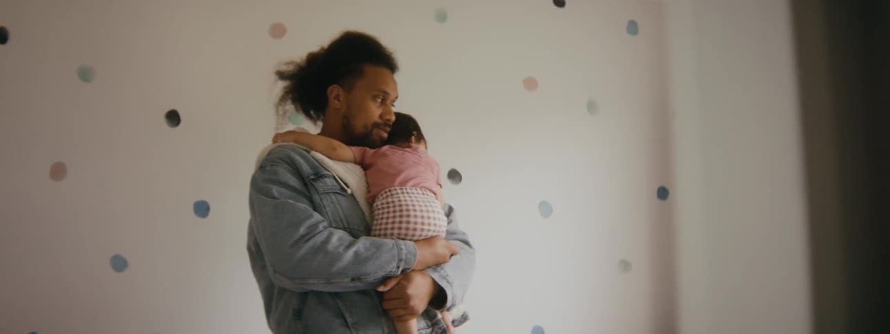 A father is holding there child in his bedroom