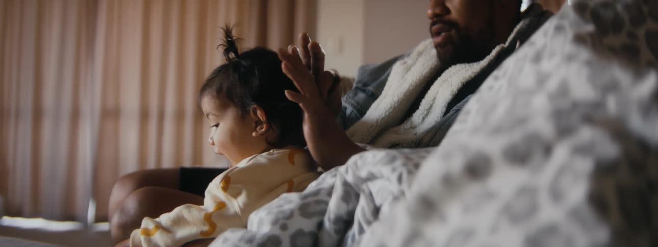 A father putting his baby daughters hair in pigtails