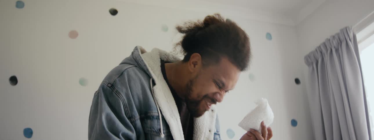 A man laughs as he holds a used diaper near a child