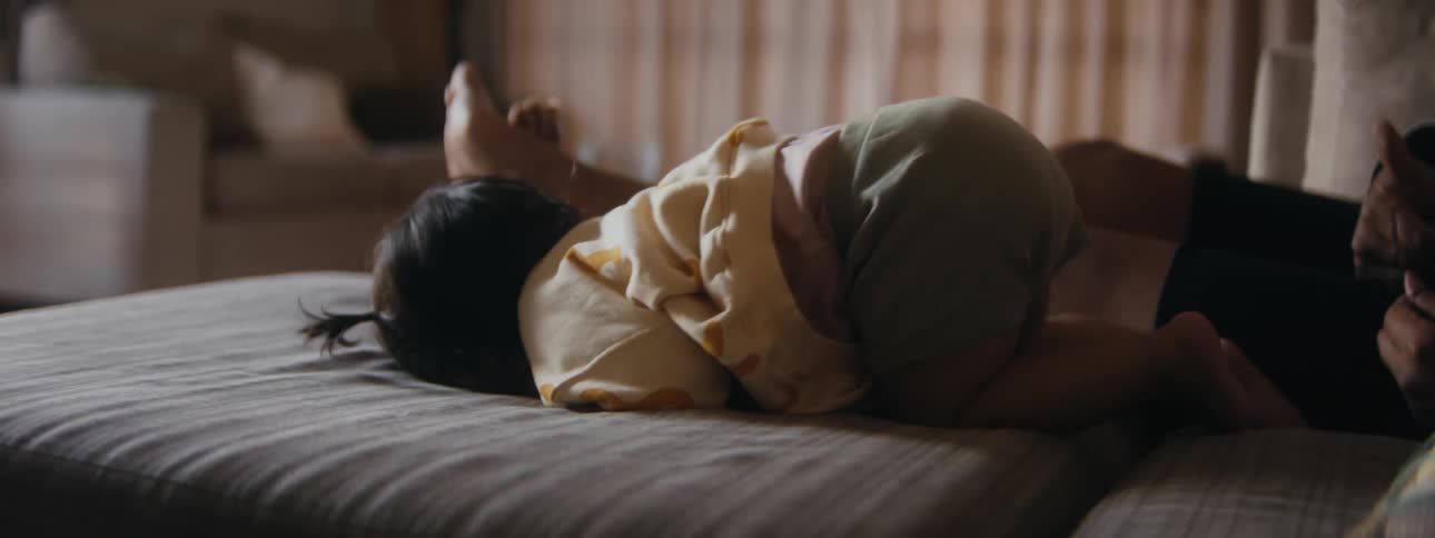 A young toddler is on the bed moving around