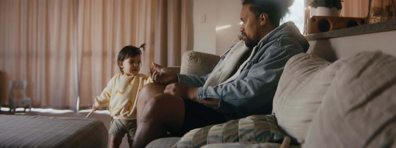 A father engaging with his toddler daughter at home on a living room sofa