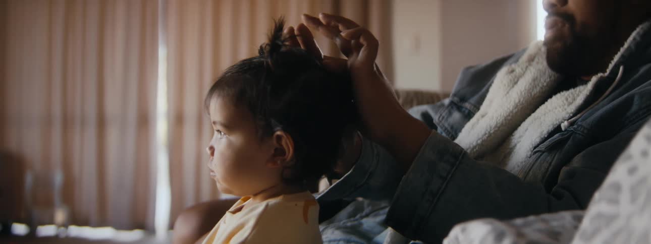 A father is playing with his daughters hair inside