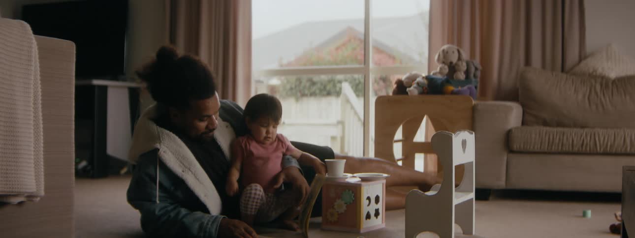 A father is reading a book to his daughter during the day time