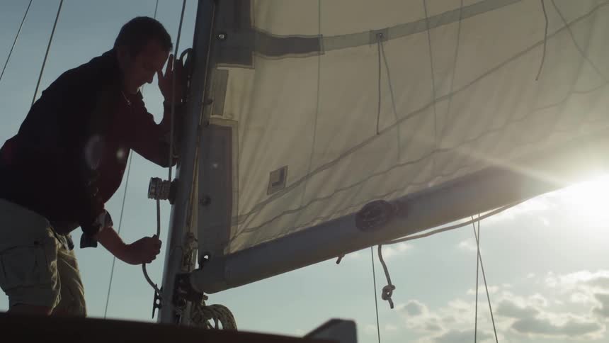 A man ties rope on a sailboat