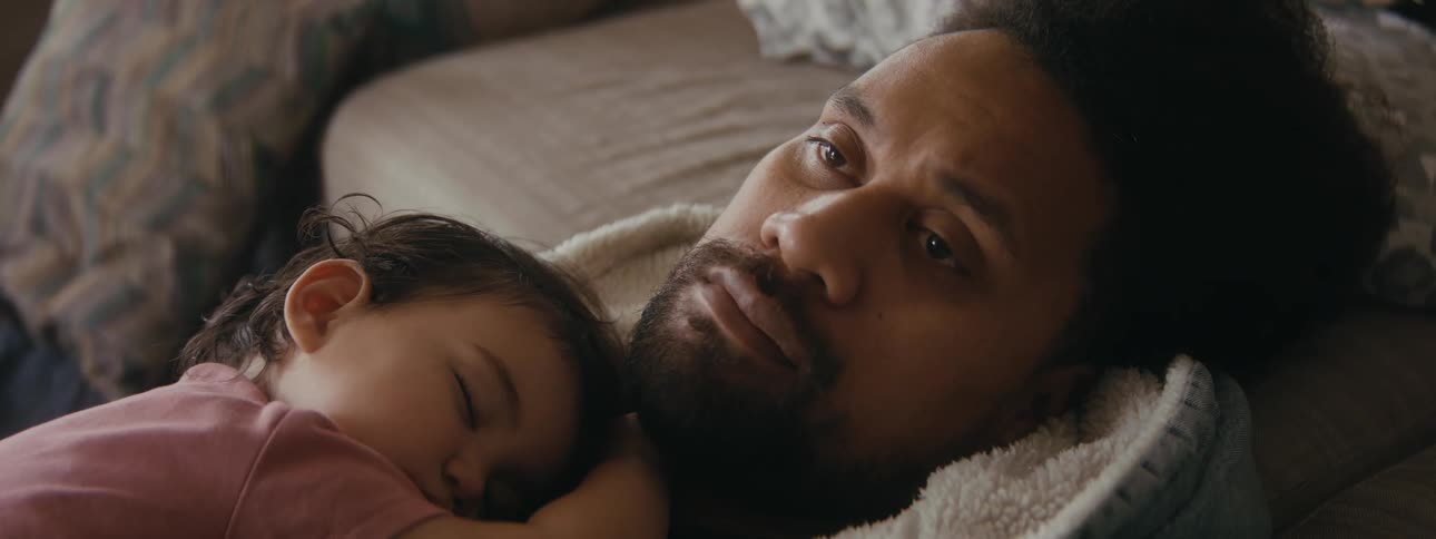 Tired and thoughtful father lying down with his daughter taking a nap on his chest