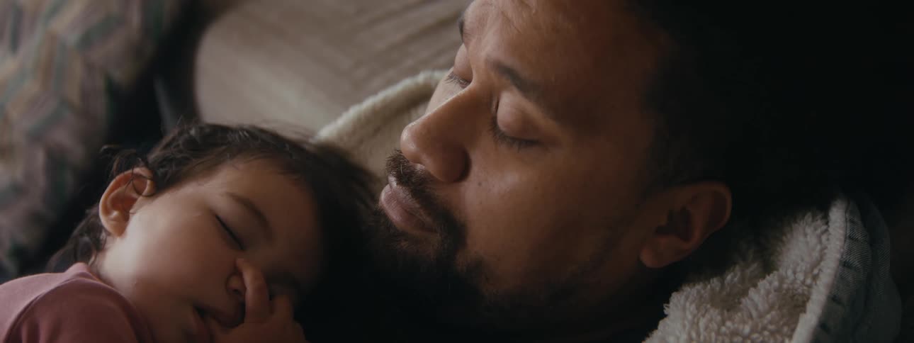 A father is taking a nap with his newborn child
