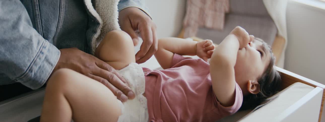 A woman changes her daughters diaper