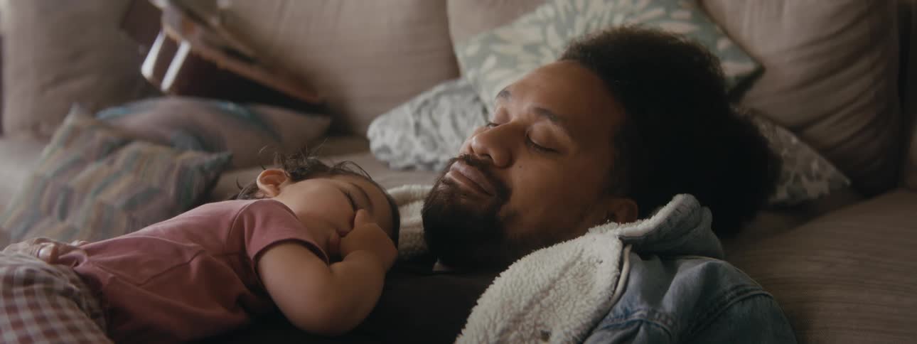 A father is resting while his newborn child lays on him