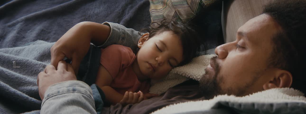 A father is holding his newborn daughter and napping