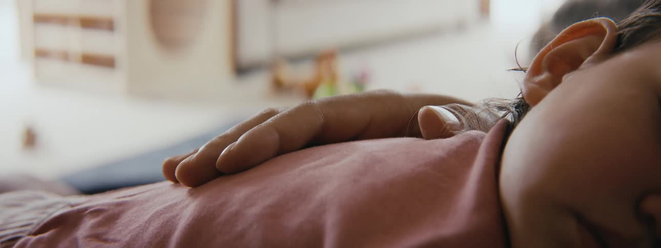 Parent pats back of sleeping child