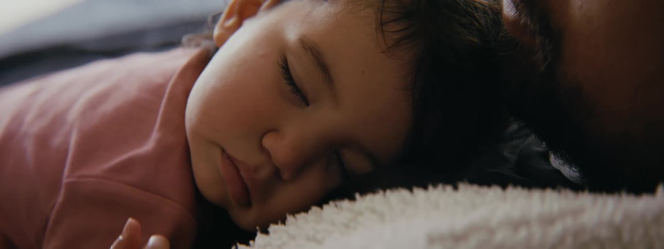 A father sleeping with a baby on his chest