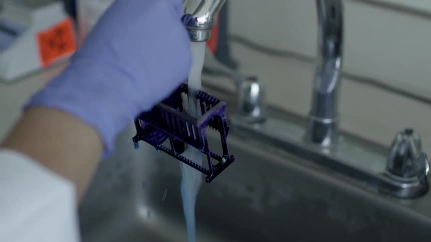 A person rinses blue liquid off of an object