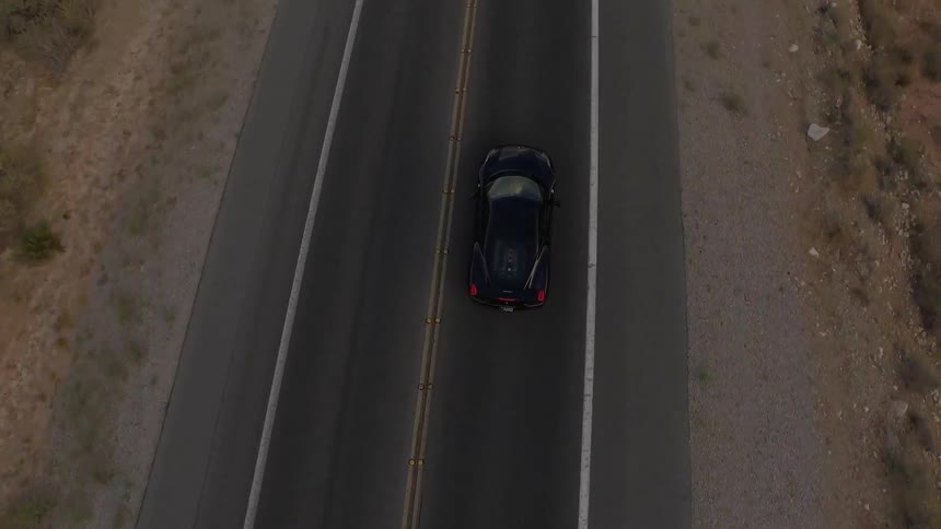 A black car drives down a road