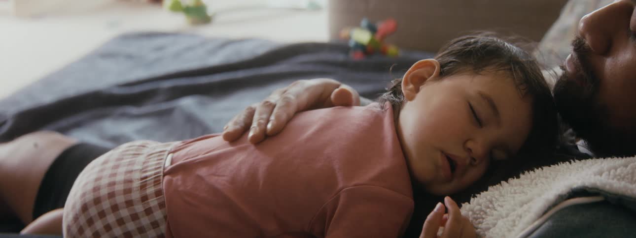 Baby sleeping on father as he caresses her back