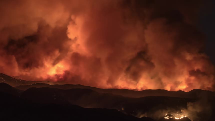 A huge cloud of smoke billows up from a destructive wildfire