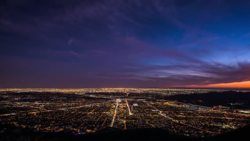 Time lapse view of a city while the sun is setting is displayed