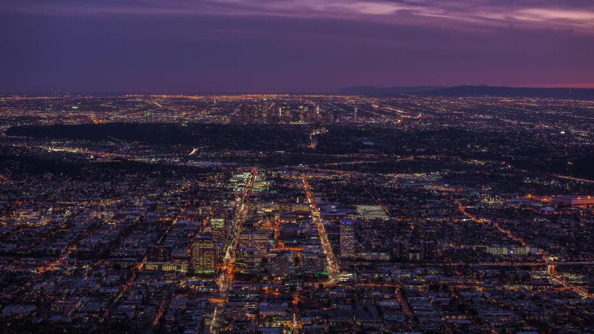 Traffic and city lights shine as night falls over cityscape