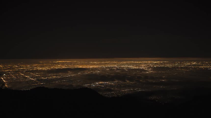 City lights shimmering at night as airplane streak through the sky coming in for a landing