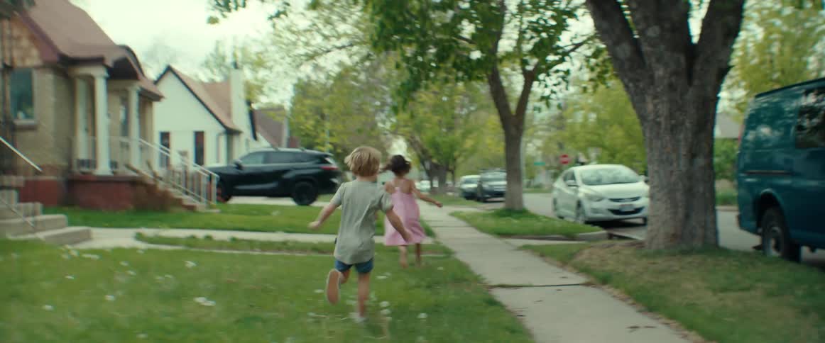 Boy chases girl through lawns in neighborhood