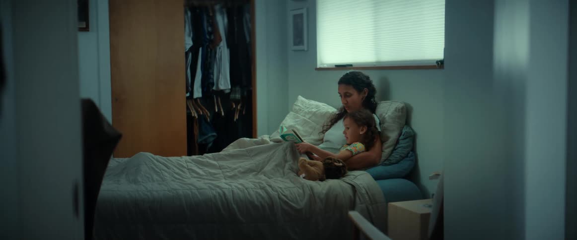 Woman lies in bed with daughter reading to her
