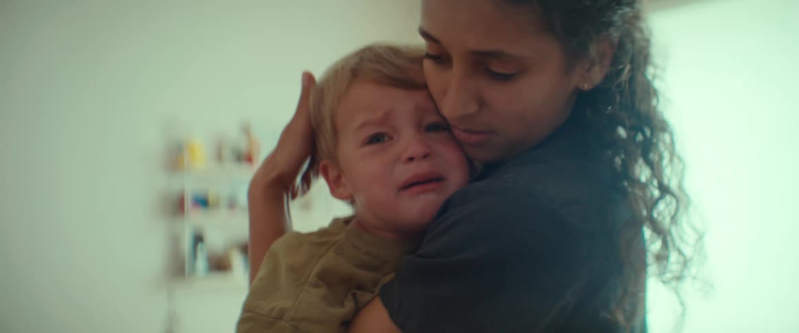 A girl is holding a toddler that is upset and crying