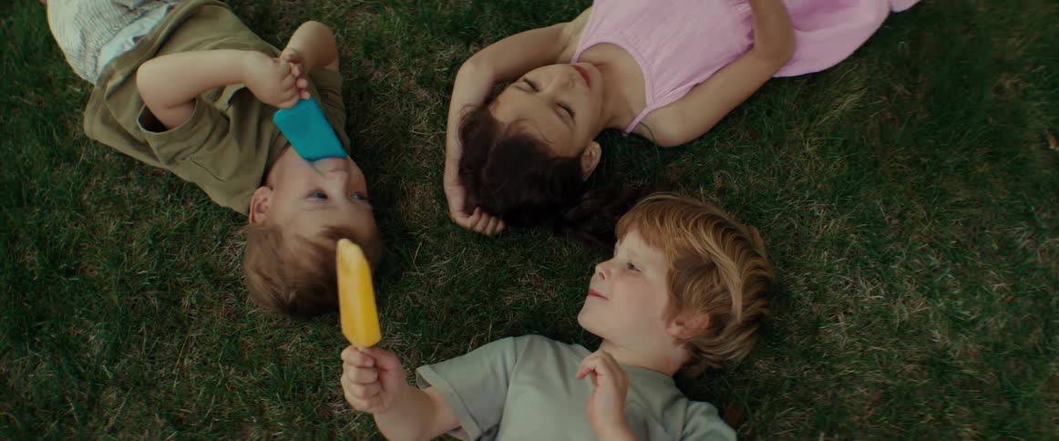 Children are laying in the grass eating popsicles
