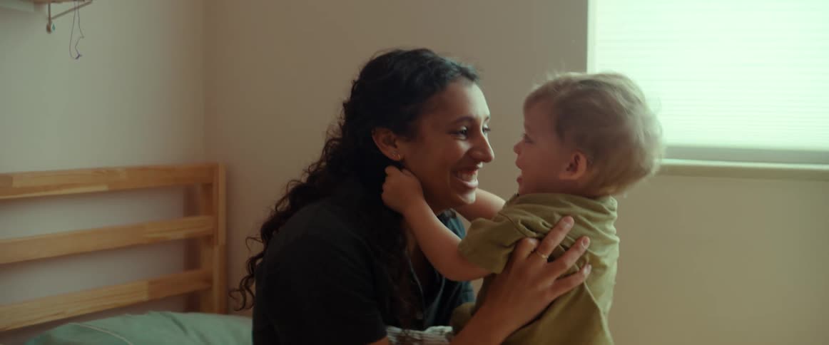 Child jumps onto mom as they play on bed