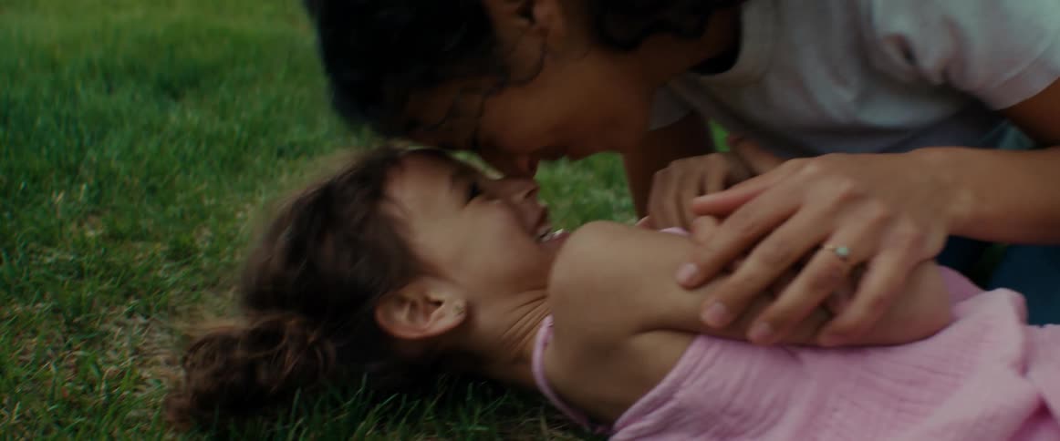 A mother plays with her daughter in the grass